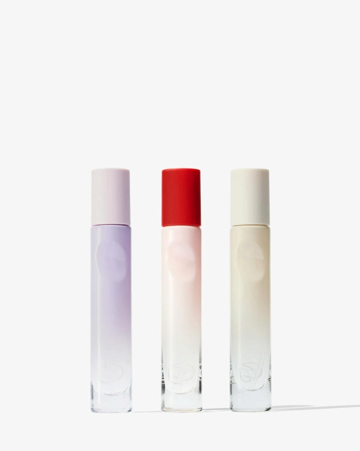 Glossier You Discovery Kit - trzy podróżne flakony z fioletową, czerwoną i kremową nakrętką na białym tle | Ellemania