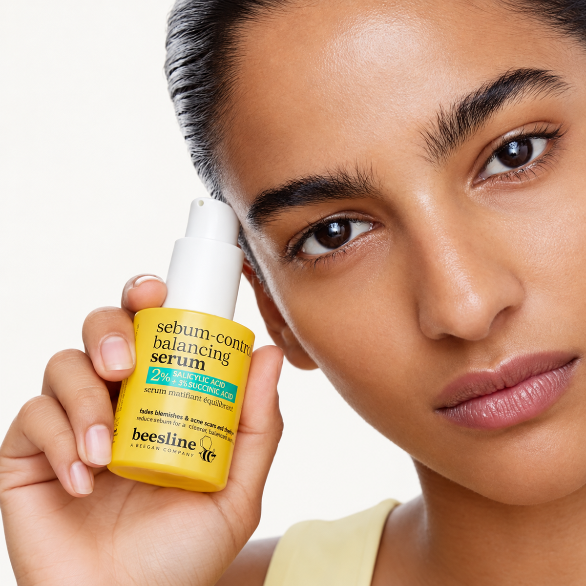Beesline Sebum-Control Balancing Serum - modelka trzyma butelkę serum przy skroni | Ellemania