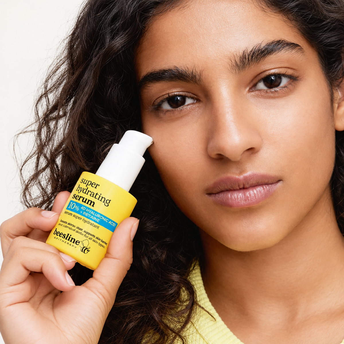 Beesline Super Hydrating Serum - modelka trzyma butelkę serum przy policzku | Ellemania
