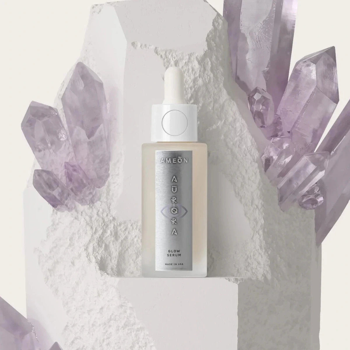 AMEON Aurora Glow Serum 30 ml, butelka z pipetą na tle kryształów i białej struktury | Ellemania