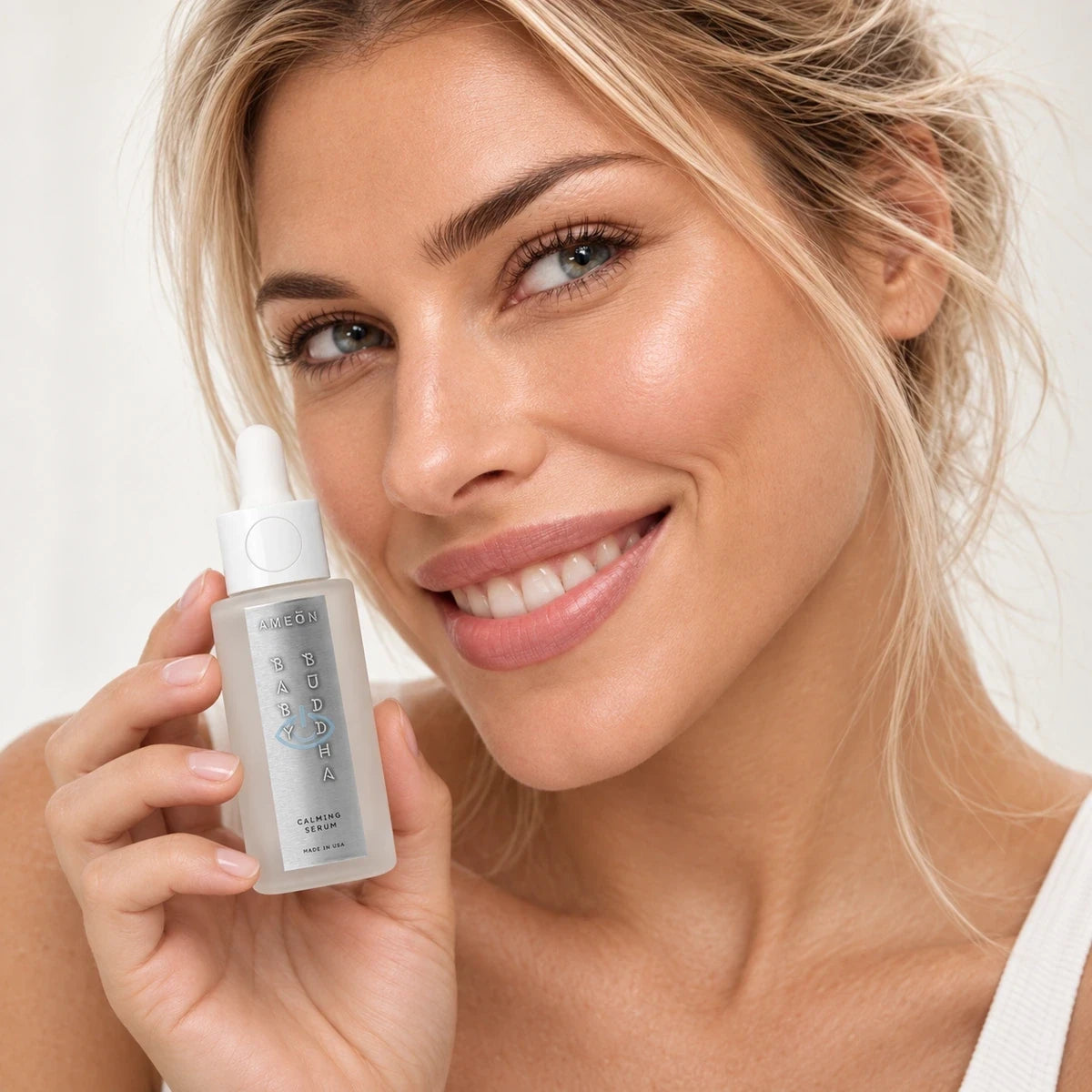 AMEON Baby Buddha Calming Serum 30 ml, uśmiechnięta kobieta trzyma butelkę z pipetą przy twarzy | Ellemania