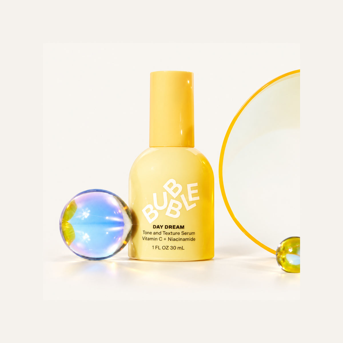 Bubble Skincare Day Dream Serum 30 ml, yellow bottle next to glass spheres and a yellow ring | Ellemania