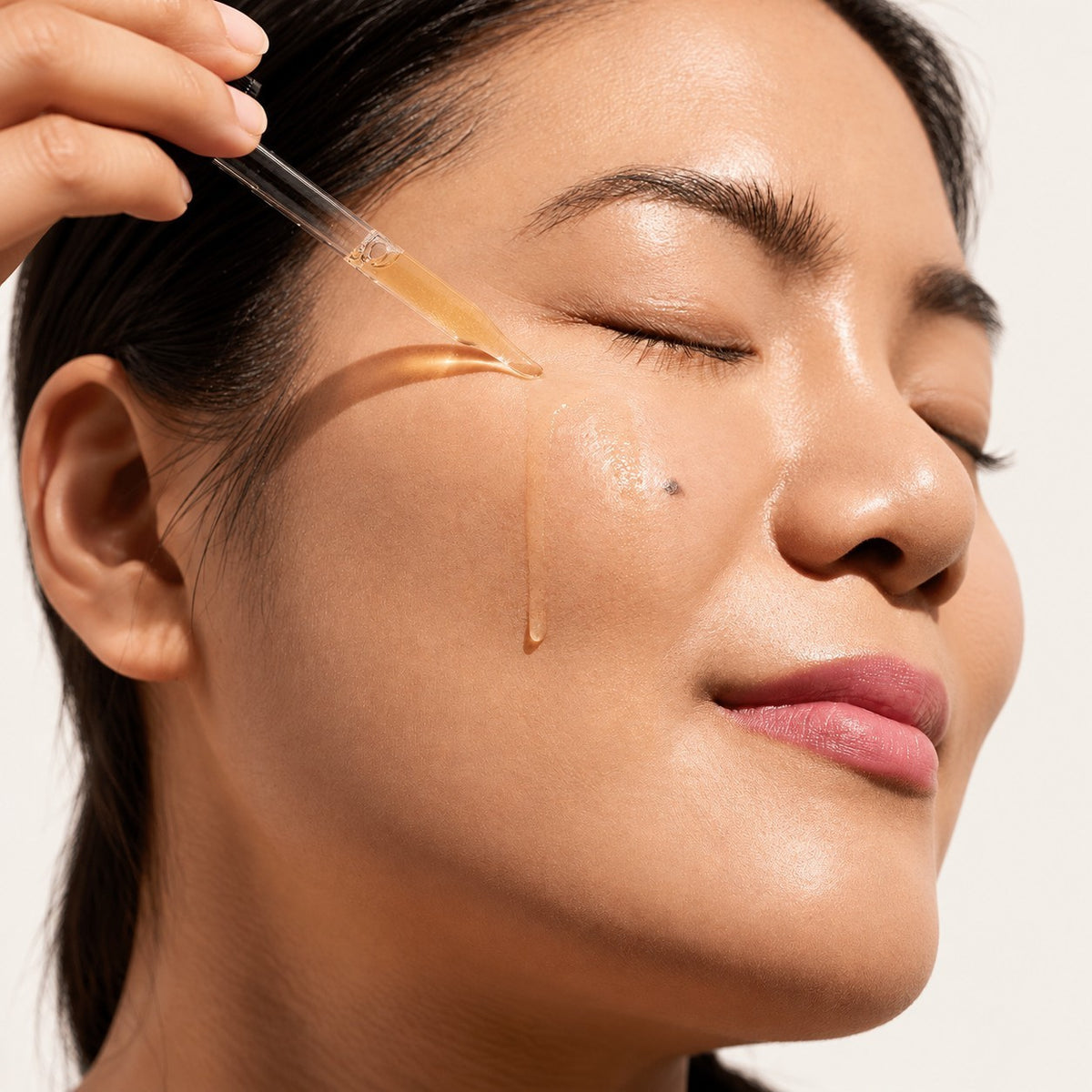 DRMTLGY Vitamin CE + F Serum 30 ml - kobieta z zamkniętymi oczami, serum nakładane pipetą na policzek | Ellemania