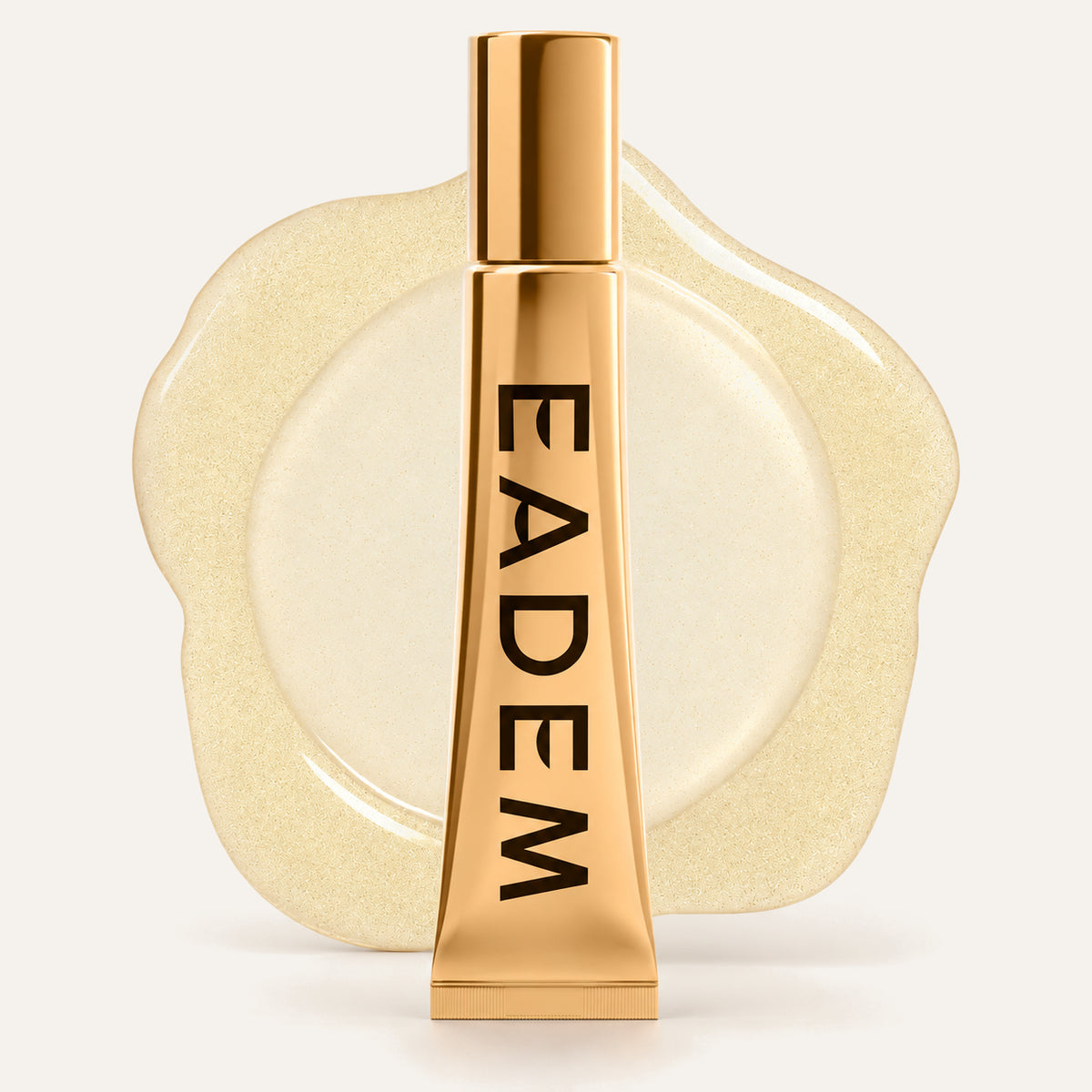 Eadem Le Chouchou Lip Softening Balm 14 ml, tubka z przodu obok złocistej, błyszczącej plamy balsamu | Ellemania
