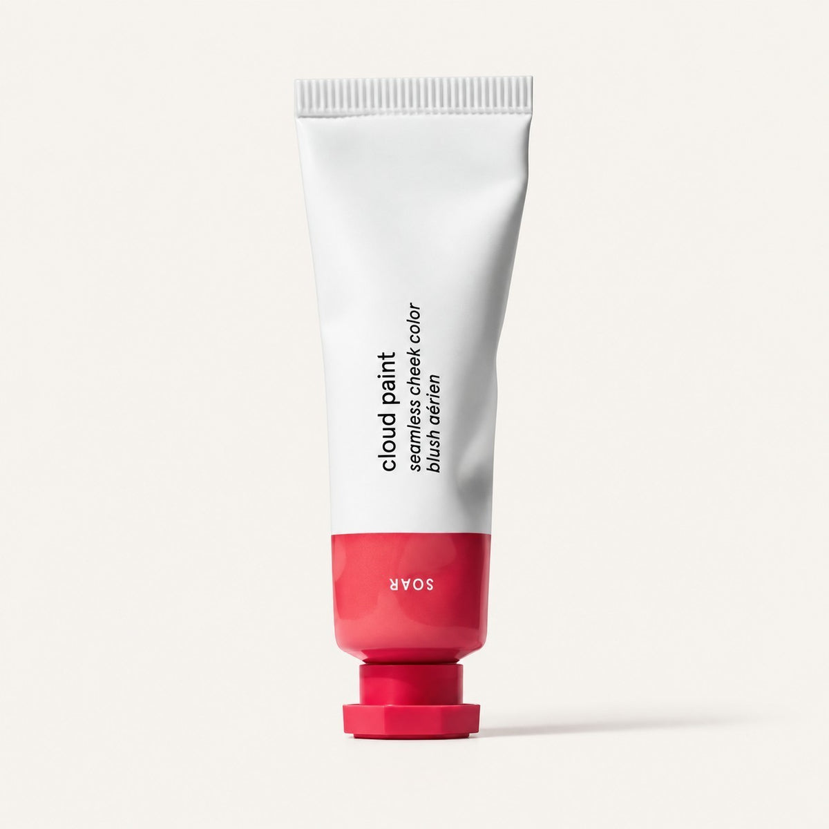 Glossier Cloud Paint - odcień Soar, biała tubka z malinowo-czerwoną końcówką i nakrętką, na opakowaniu napis Soar, jasne tło | Ellemania