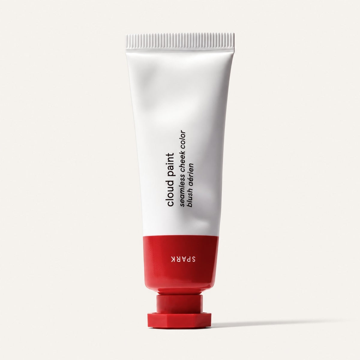 Glossier Cloud Paint - odcień Spark, biała tubka z czerwoną końcówką i nakrętką, na opakowaniu napis Spark, jasne tło | Ellemania