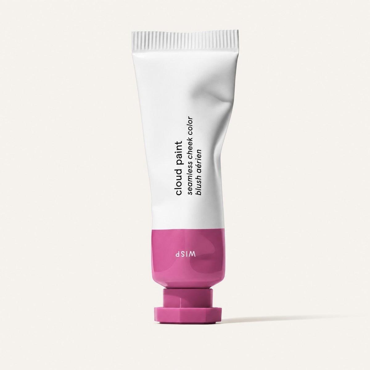 Glossier Cloud Paint - odcień Wisp, zgnieciona biała tubka z różowo-fiołkową końcówką i nakrętką, na opakowaniu napis Wisp, jasne tło | Ellemania