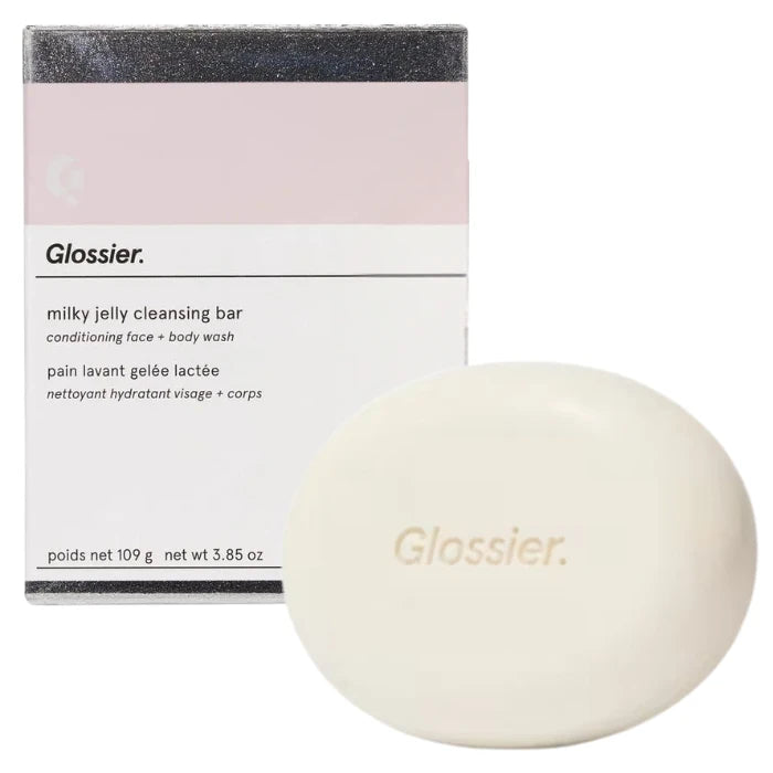 Glossier Milky Jelly Cleansing Bar 109 g - kremowa owalna kostka myjąca z wytłoczonym logo przed pudełkiem z różowym paskiem | Ellemania