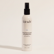 Biała butelka mgiełki termoochronnej Kitsch Heat Protectant & Styling Mist z czarnym atomizerem na jasnym tle.