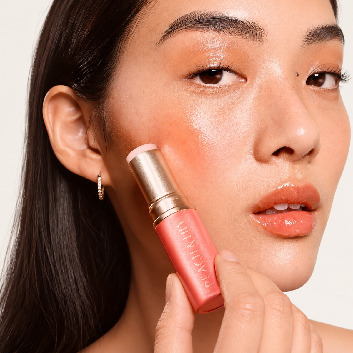 Peach & Lily Glass Skin Luminizing Stick - modelka przykłada sztyft do policzka | Ellemania