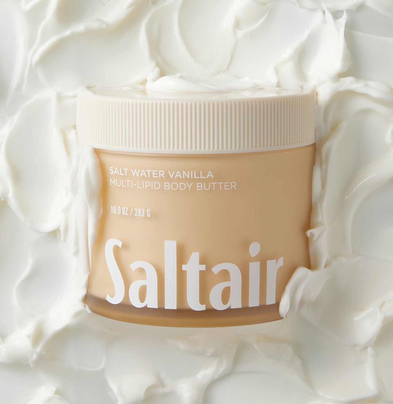 Słoiczek masła do ciała Saltair Multi-Lipid w zapachu Salt Water Vanilla zanurzony w kremowej konsystencji produktu