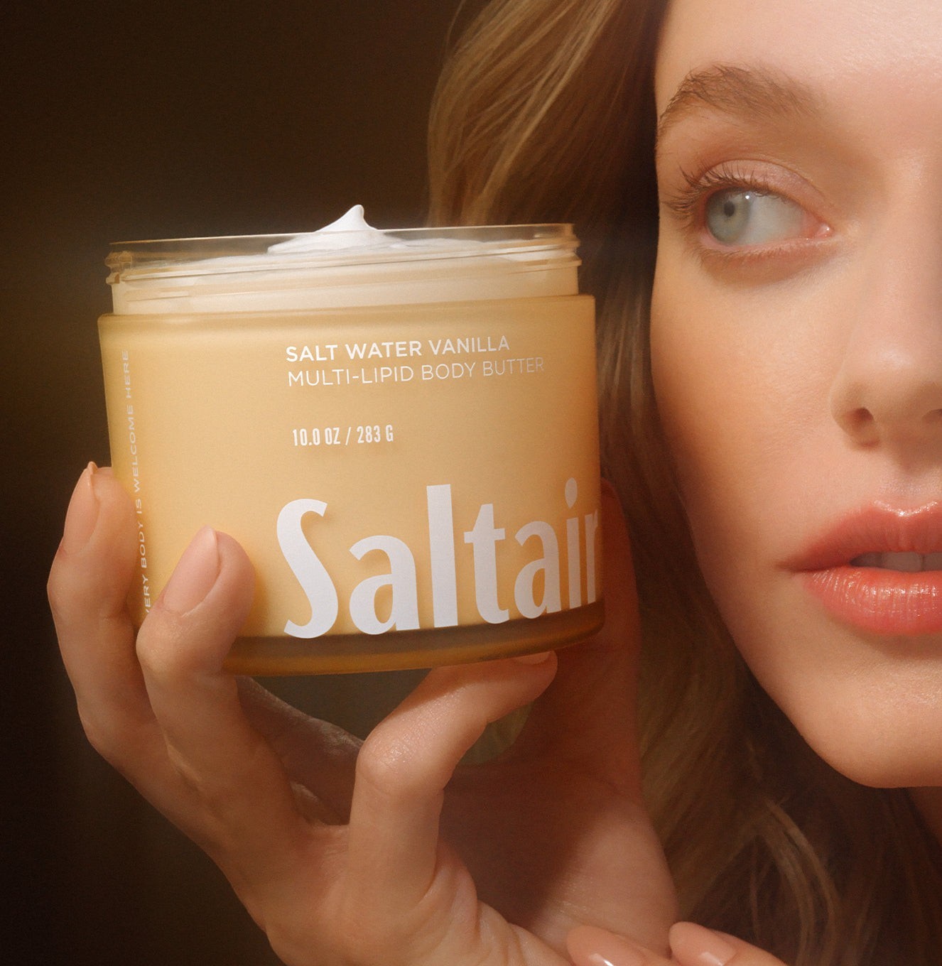 Kobieta trzymająca słoiczek masła do ciała Saltair Multi-Lipid Body Butter o zapachu Salt Water Vanilla od ellemania
