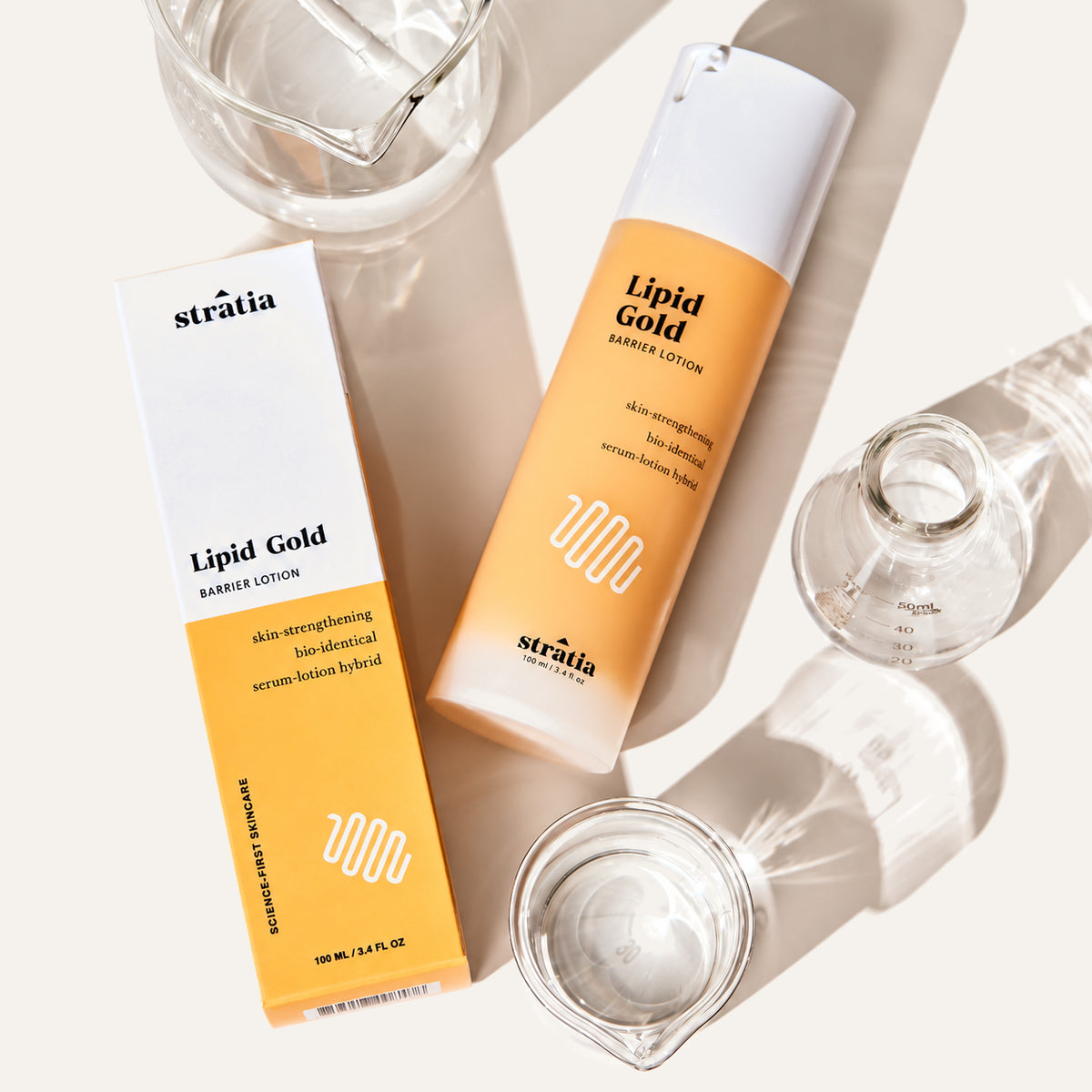 Stratia Lipid Gold, box and bottle with a pump, front view, beside glasses | Ellemania