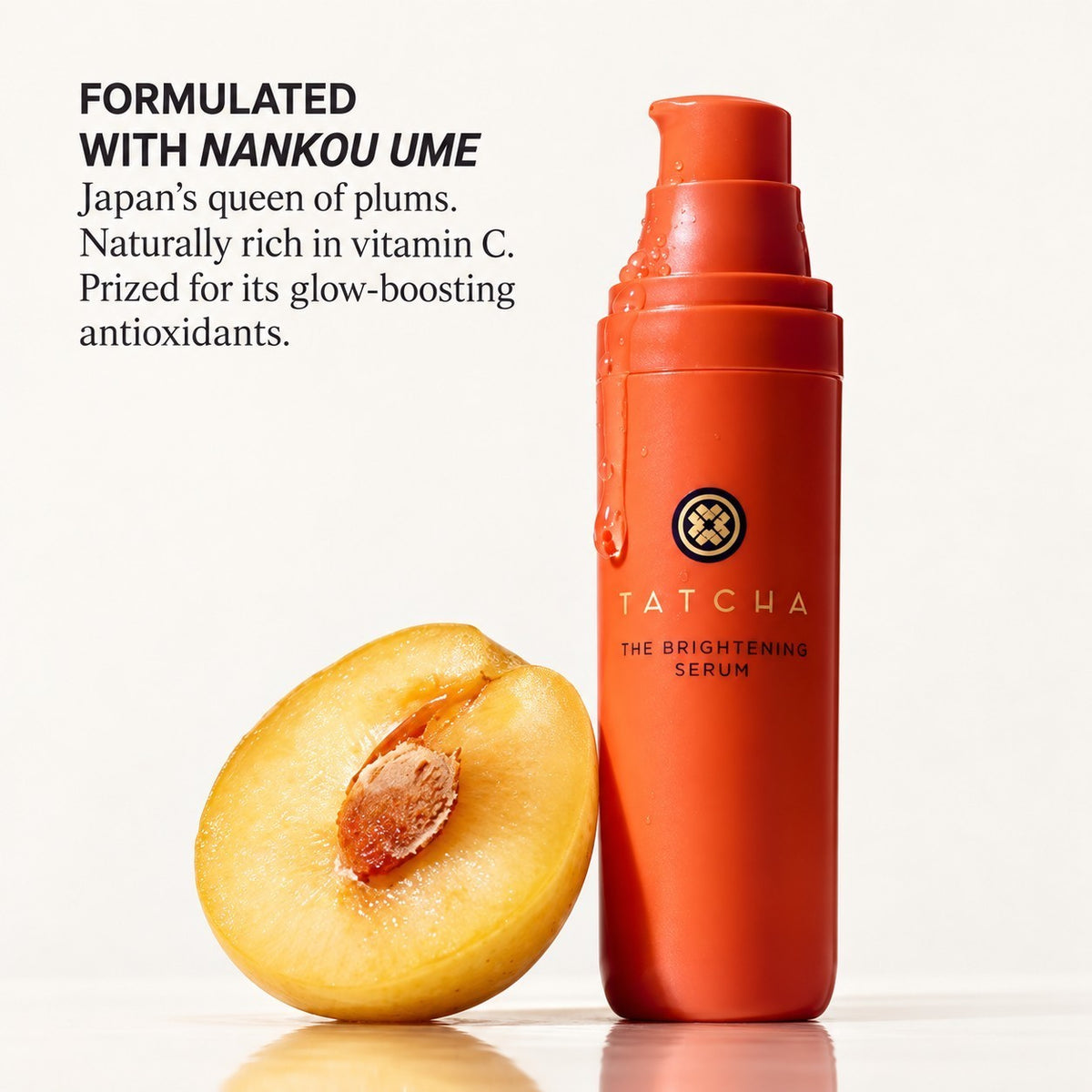 Tatcha The Brightening Serum, pomarańczowa butelka z pompką obok przekrojonej śliwki | Ellemania