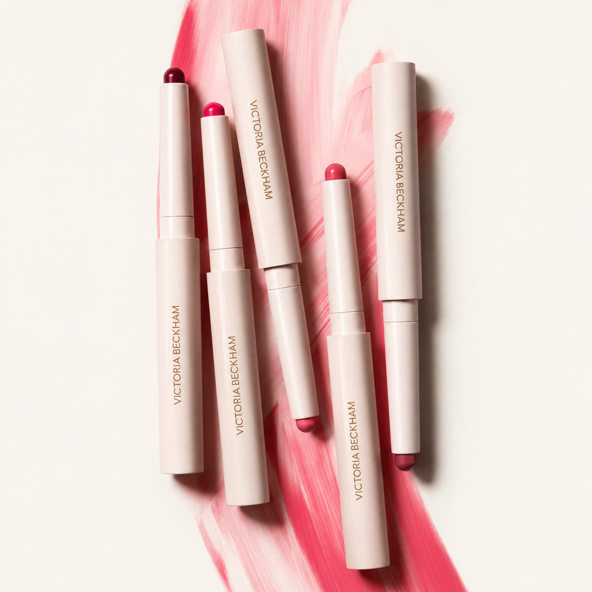 Victoria Beckham Beauty Blush Stylus - pięć sztyftów w kremowych obudowach ułożonych na różowej smudze koloru | Ellemania