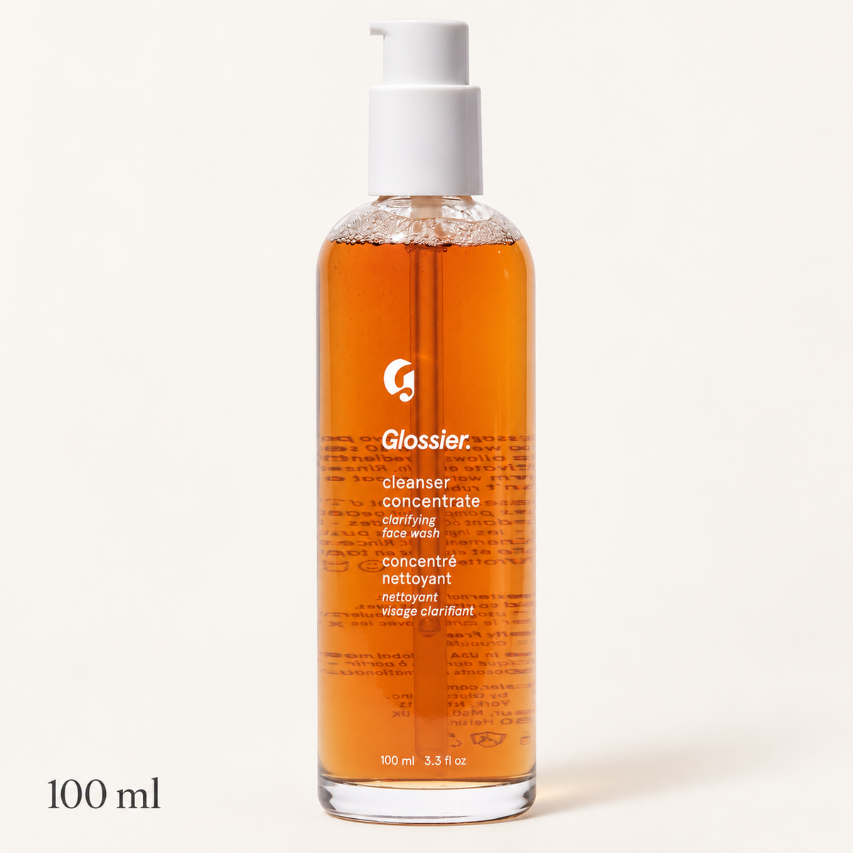 Glossier Cleanser Concentrate - butelka z pompką i białą głowicą wypełniona bursztynowym płynem, napis 100 ml, na jasnym tle | Ellemania