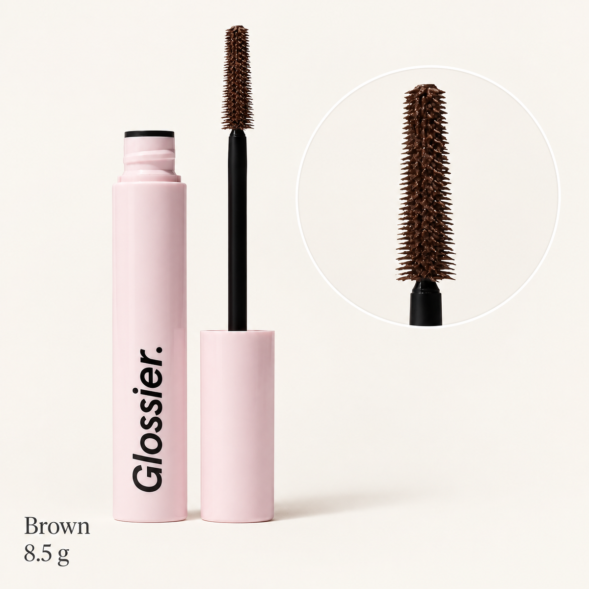 Glossier Lash Slick Brown - otwarty tusz do rzęs z brązową szczoteczką w różowej obudowie z czarnym napisem Glossier, obok powiększenie szczoteczki, podpis Brown 8.5 g, na jasnym tle | Ellemania