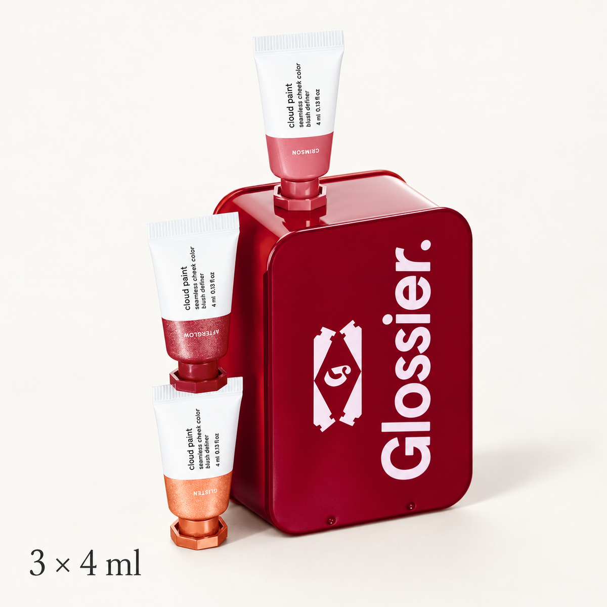 Glossier Mini Cloud Paint Trio - czerwone metalowe pudełko z logo Glossier i trzy tubki z podpisami Crimson, Afterglow i Glisten ustawione na nim i obok, napis 3 × 4 ml na jasnym tle | Ellemania