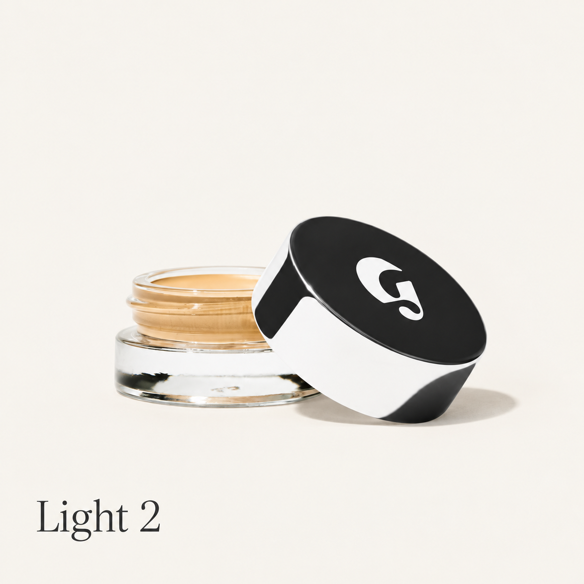 Glossier Stretch Balm Concealer - odcień Light 2, szklany słoiczek ze złocisto-beżowym korektorem i czarno-białą nakrętką z logo na jasnym tle | Ellemania