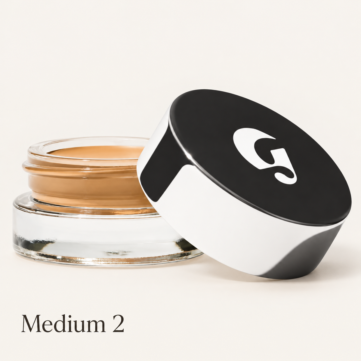 Glossier Stretch Balm Concealer - odcień Medium 2, szklany słoiczek ze złocisto-karmelowym korektorem i czarno-białą nakrętką z logo na jasnym tle | Ellemania