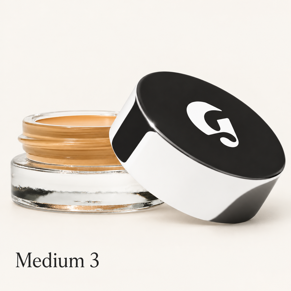 Glossier Stretch Balm Concealer - odcień Medium 3, szklany słoiczek z miodowo-złocistym korektorem i czarno-białą nakrętką z logo na jasnym tle | Ellemania