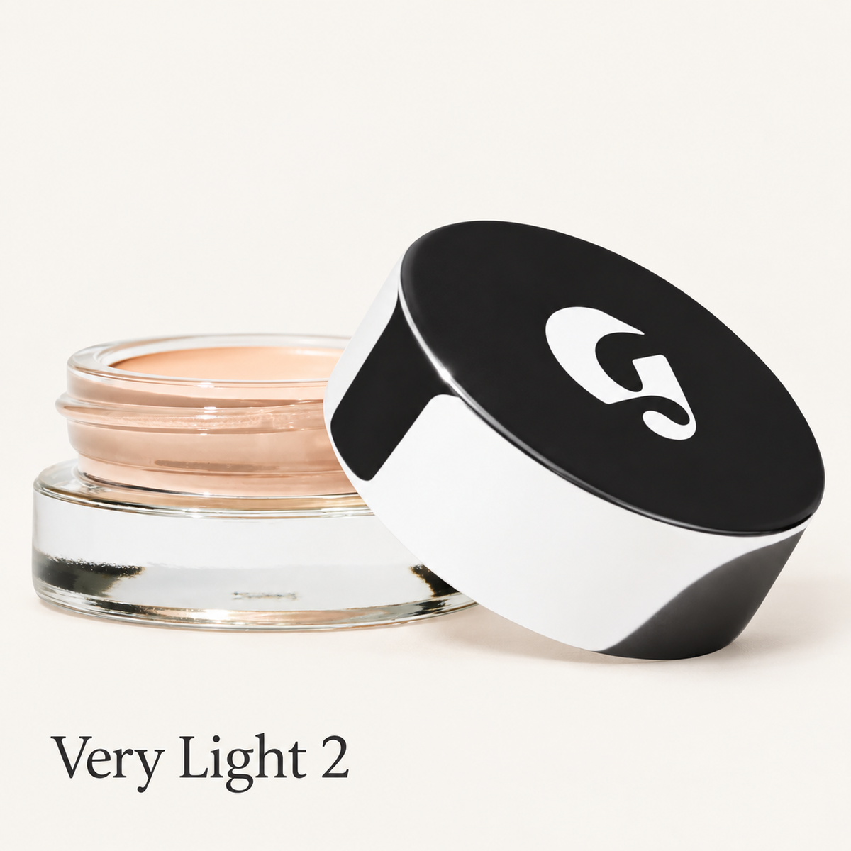 Glossier Stretch Balm Concealer - odcień Very Light 2, szklany słoiczek z jasnym brzoskwiniowo-beżowym korektorem i czarno-białą nakrętką z logo na jasnym tle | Ellemania