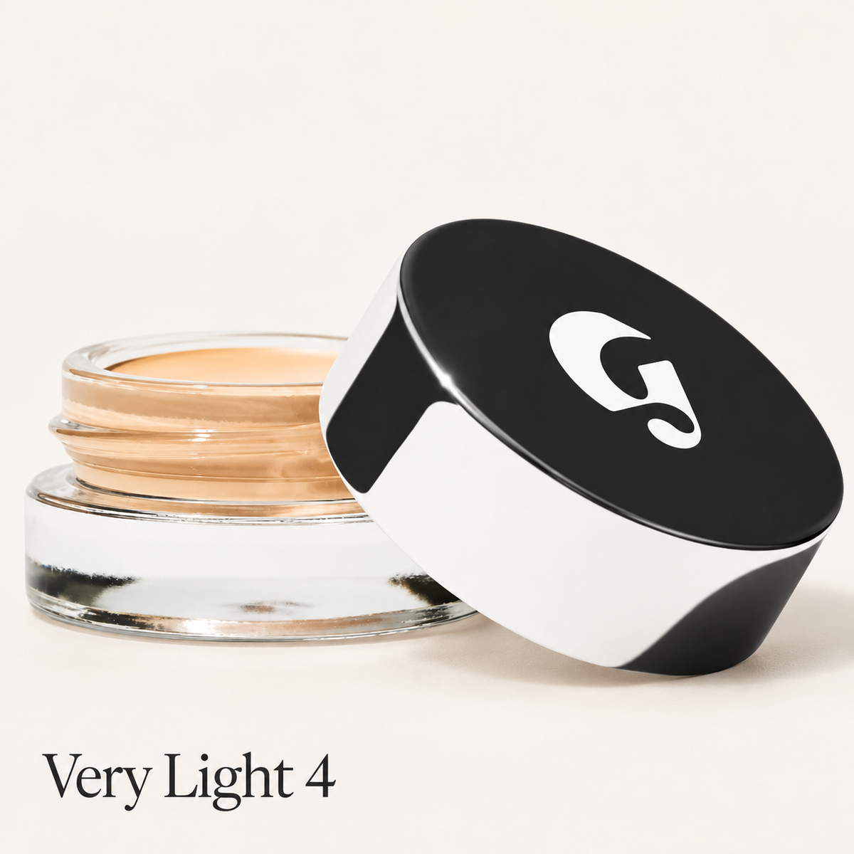 Glossier Stretch Balm Concealer - odcień Very Light 4, szklany słoiczek z jasnym złocisto-beżowym korektorem i czarno-białą nakrętką z logo na jasnym tle | Ellemania
