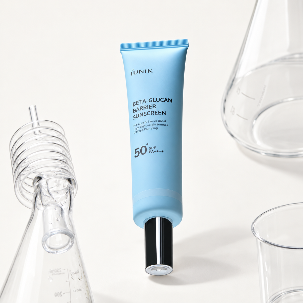 IUNIK Beta-Glucan Barrier Sunscreen - tubka z czarną końcówką wśród szklanych naczyń laboratoryjnych | Ellemania